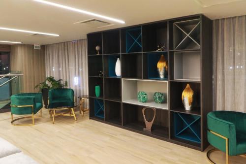 a living room with green chairs and a book shelf at Holiday Inn & Suites - Mexico Felipe Angeles Airport by IHG in Zumpango de Ocampo