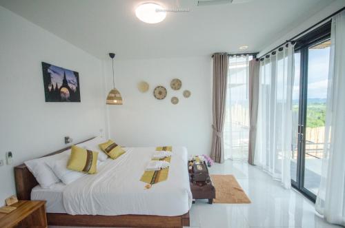 a white bedroom with a bed and a large window at Caligo Resort in Ban Pha Saeng Lang