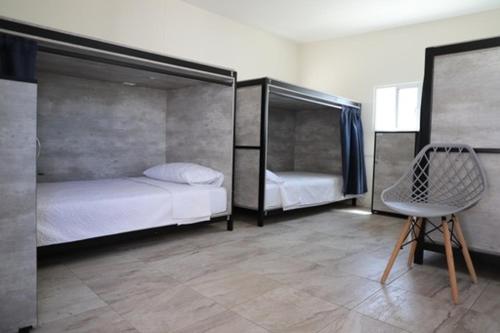 una camera con due letti e una sedia di HOSTAL XAO a Città di Oaxaca