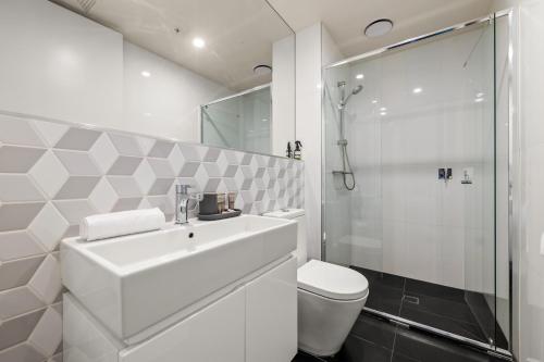 a white bathroom with a sink and a shower at StayCentral - Hawthorn East - Study, 2 Car spaces in Melbourne
