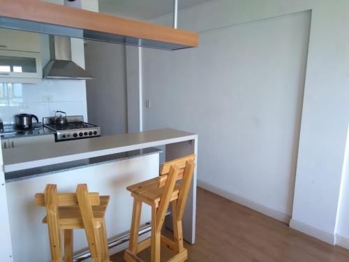 cocina con 2 sillas de madera y encimera en Alojamiento Bariloche – Departamento céntrico con vistas al Lago Nahuel Huapi en San Carlos de Bariloche