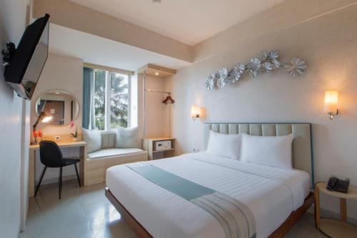 a bedroom with a bed and a desk and a television at Solaris Hotel Malang in Malang