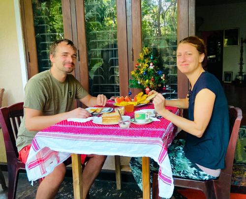 Green Grass Homestay في سيجيريا: رجل وامرأة يجلسان على طاولة ويتناولان الطعام