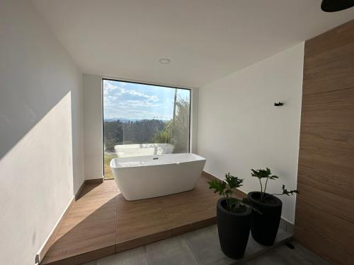 ein Badezimmer mit einer weißen Badewanne und einem großen Fenster in der Unterkunft Casa Río Quindío in La Tebaida