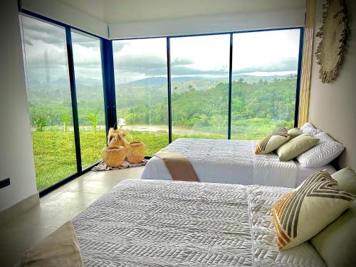 um quarto com 2 camas e uma grande janela em Casa Río Quindío em La Tebaida