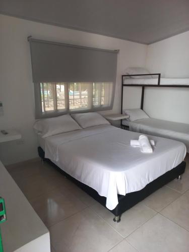 a bedroom with a large white bed and a window at VILLA GLADHYS CASA CAMPESTRE in Honda