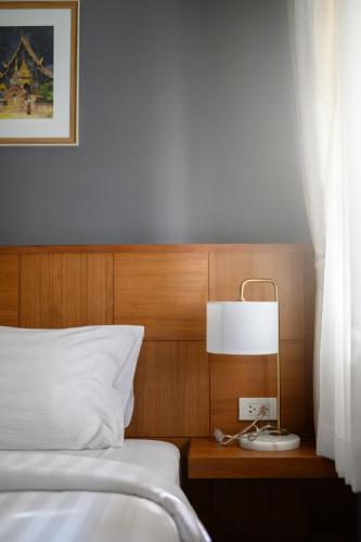 a bedroom with a bed and a lamp on a table at Estia Chiangmai in Chiang Mai