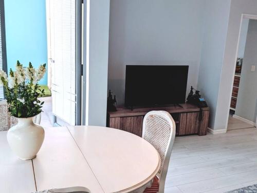 a white table and chairs in a living room with a television at On The Beach at Surfers Corner in Cape Town