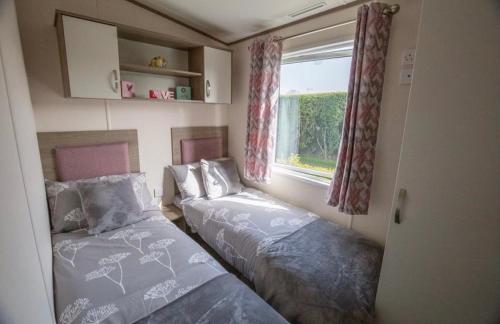 1 dormitorio con 2 camas y ventana en Pepper Pot Lodge en Knaresborough