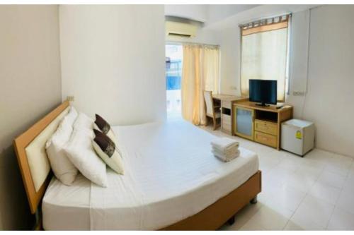 OYO 75418 Grandview Place في بانكوك: غرفة نوم بسرير ومخدات وتلفزيون