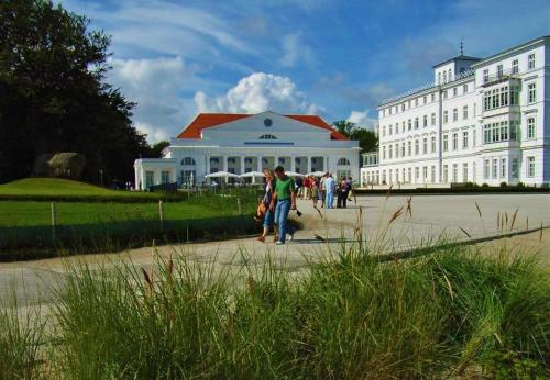 Un groupe de personnes debout devant un grand bâtiment blanc dans l'établissement Ostsee Hotel-Pension An der Lindenallee, à Bad Doberan