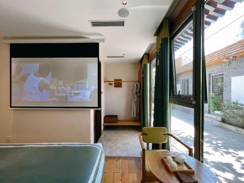 a room with a bed and a table and windows at Beijing Heyuan Courtyard Hotel (Forbidden City) in Beijing