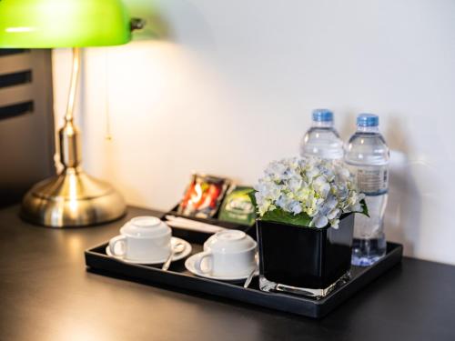 a tray with a vase of flowers and cups and water bottles at The Flower Boutique Hotel & Travel in Hanoi