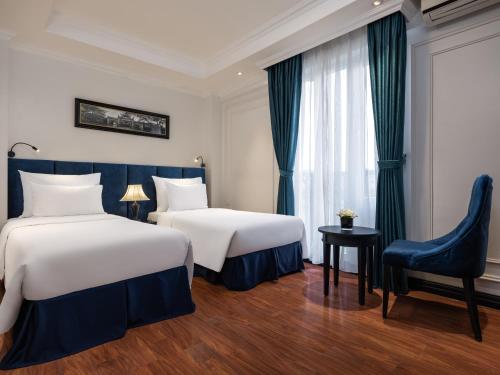 a hotel room with two beds and a chair at The Flower Boutique Hotel & Travel in Hanoi