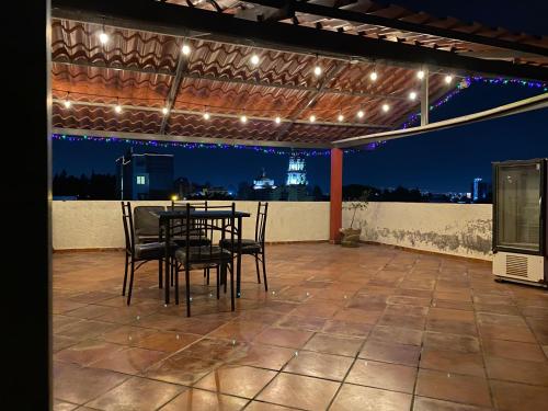 a patio with a table and chairs and lights at Departamento con Terraza LOBO in Cholula