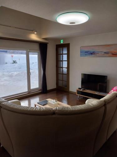 een woonkamer met een bank en een televisie bij Miyuki Townhouse in Furano