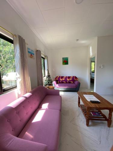 a living room with a purple couch and a table at Anse Grosse Roche Beach Villa in La Digue