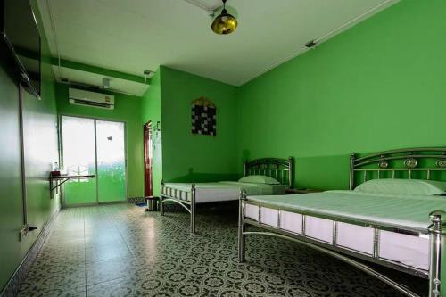 a green room with two beds and a window at 2U Hotel Hatyai in Hat Yai