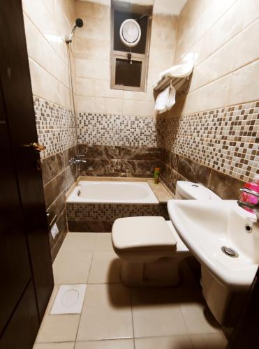 een badkamer met een toilet, een wastafel en een bad bij noor apartment in Wadi Musa
