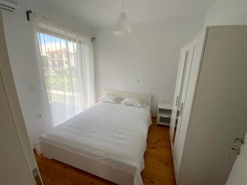 a white bedroom with a white bed and a window at F.R. House in Metamorfosi