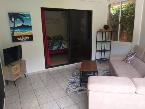 a living room with a couch and a tv at Vacation house in Tahiti in Punaauia