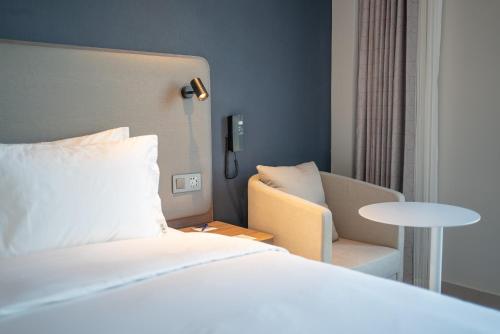 a hotel room with a bed and a chair at Holiday Inn Express Qingdao Northern West Coast by IHG in Qingdao