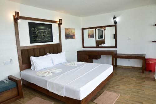 a bedroom with a bed and a desk and a mirror at New Ocean Hill Hotel in Hikkaduwa