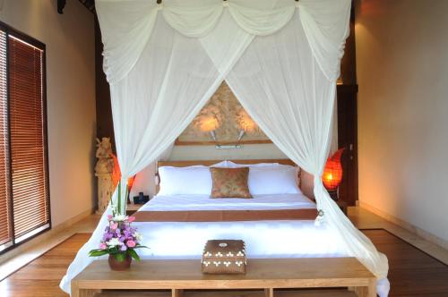 a bedroom with a bed with a canopy at Villa DiKebun in Uluwatu