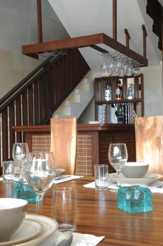 a wooden table with glasses and plates on it at Villa DiKebun in Uluwatu