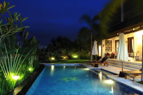 a swimming pool in a backyard at night at Villa DiKebun in Uluwatu