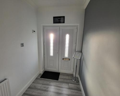 a hallway with a white door and a sign above it at Eastend Apartments in London