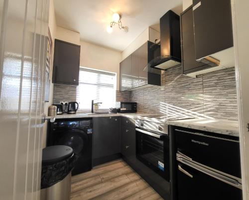 ロンドンにあるEastend Apartmentsのキッチン(黒いキャビネット、洗濯機、乾燥機付)