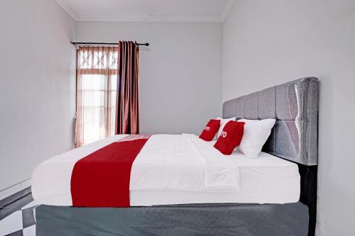 Schlafzimmer mit einem roten und weißen Bett und einem Fenster in der Unterkunft OYO 92067 Sekar Gadung Homestay Syariah in Yogyakarta