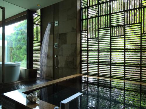 een badkamer met een douche, een wastafel en een bad bij Sankara Hotel & Spa Yakushima in Yakushima