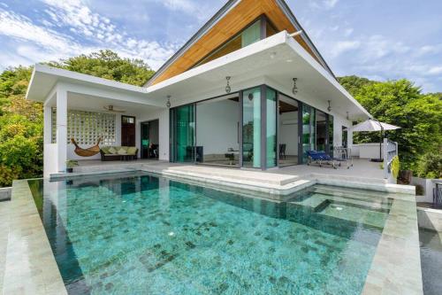 a villa with a swimming pool in front of a house at Stunning SeaView Pool Villa in Haad Pleayleam