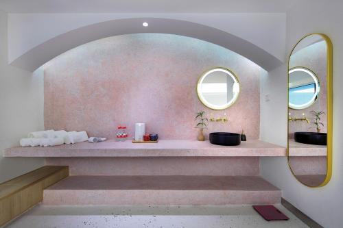 a bathroom with a pink wall with two mirrors at Sky Garden Inn in Guilin