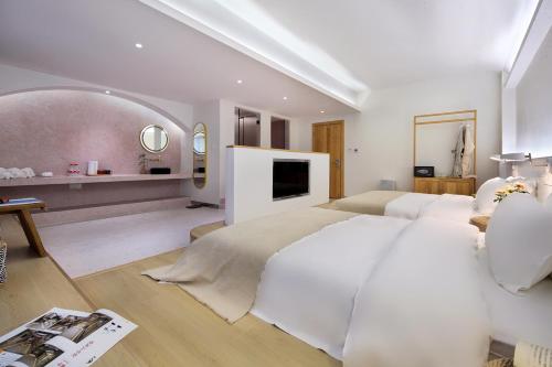 a white bedroom with a large bed and a tv at Sky Garden Inn in Guilin
