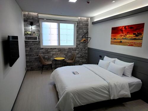 a bedroom with a bed and a table and a window at Hi& Hotel in Pyeongtaek