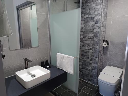 a bathroom with a sink and a toilet and a mirror at Hi& Hotel in Pyeongtaek