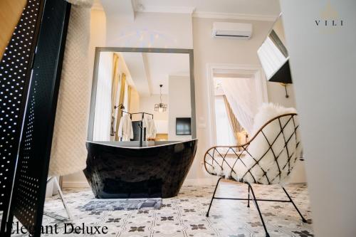 La salle de bains est pourvue d'une baignoire, d'une chaise et d'un miroir. dans l'établissement Vili Apartments, à Oradea
