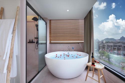 a bath tub in a bathroom with a large window at Sky Garden Inn in Guilin