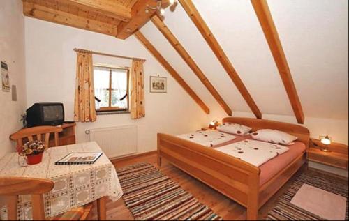 a bedroom with a bed and a table and a window at Gasthof-Pension Kesslsimerhof in Neualbenreuth