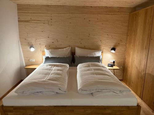 - un grand lit dans une chambre dotée d'un mur en bois dans l'établissement Mächlerhof, 