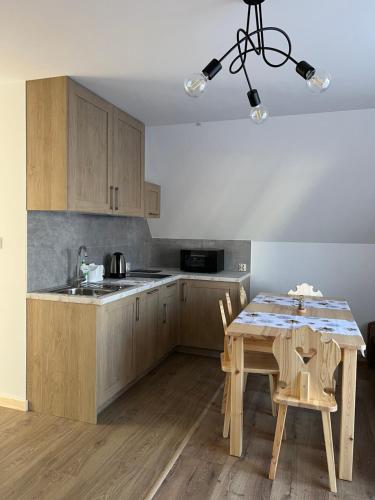 a kitchen with wooden cabinets and a table with chairs at Pokoje u Danusi in Czarna Góra