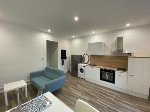 ein Wohnzimmer mit einem blauen Sofa und einer Küche in der Unterkunft Le pasteur Charmant appartement tout confort in Unieux