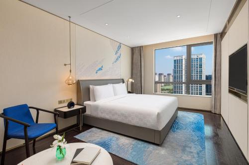 una camera con un letto, una sedia blu e una finestra di HUALUXE Shanghai Changfeng Park, an IHG Hotel a Shanghai