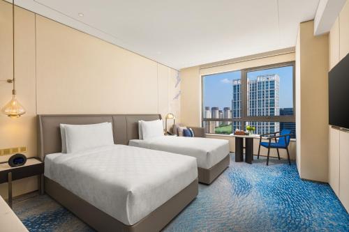 a hotel room with two beds and a large window at HUALUXE Shanghai Changfeng Park - Park Lake View in Shanghai