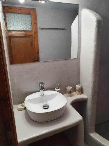 uma casa de banho com um lavatório branco e um espelho. em Traditional house under the castle em Astypalaia