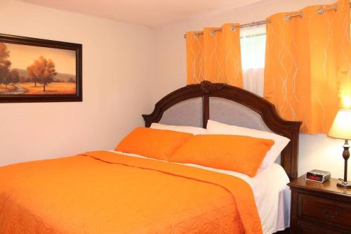 um quarto com uma cama laranja e uma janela em 2-Bedroom basement suite with a separate entrance. em Abbotsford