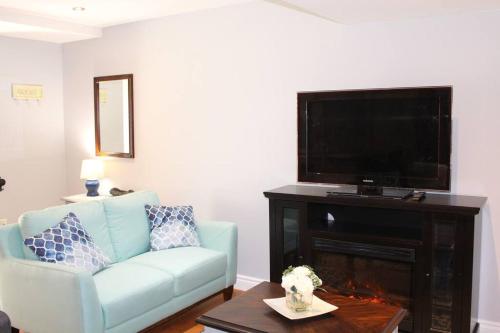 a living room with a blue couch and a flat screen tv at 2-Bedroom basement suite with a separate entrance. in Abbotsford
